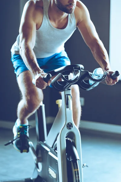 Young man cycling at gym