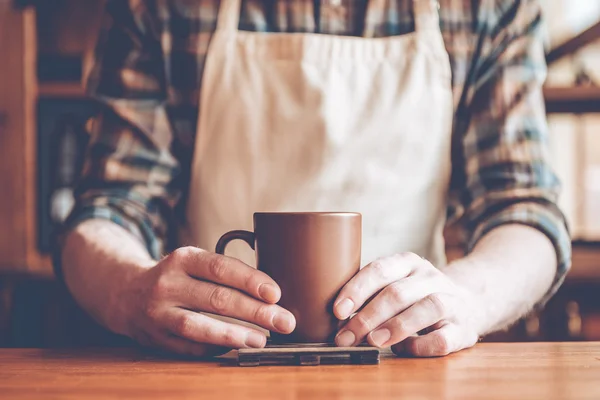 Man in apron holding coffee cup