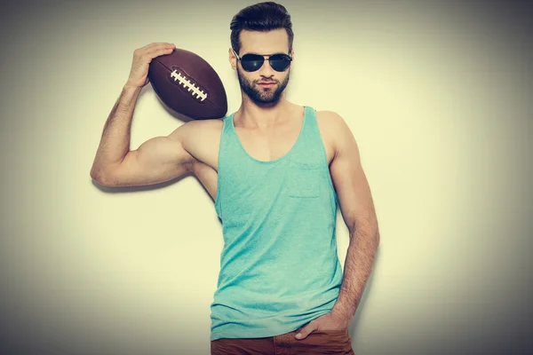Man in sunglasses carrying American football ball