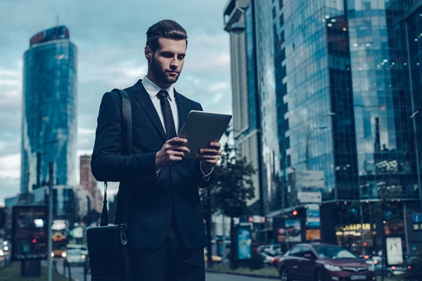 Young man in full suit holding digital tablet