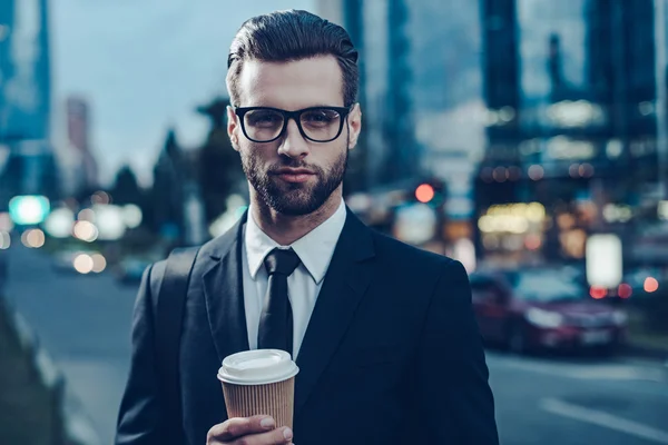 Man in full suit holding coffee cup