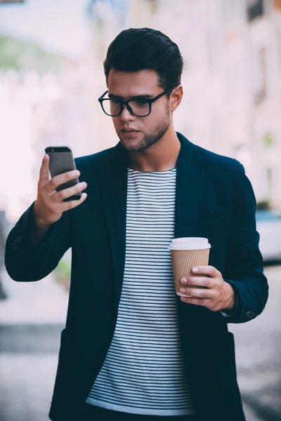 Man holding coffee and smart phone
