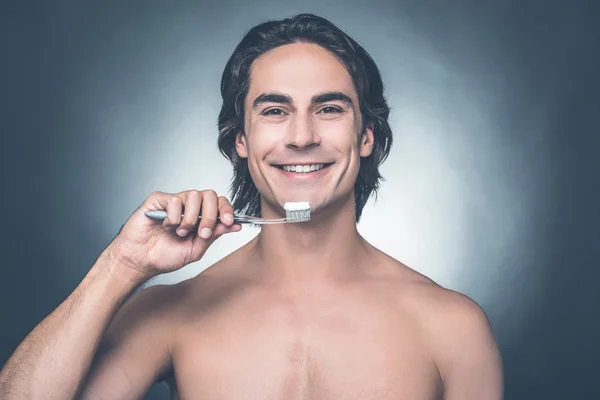 Shirtless man brushing teeth