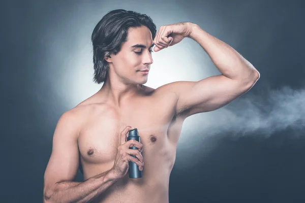 shirtless man spraying deodorant