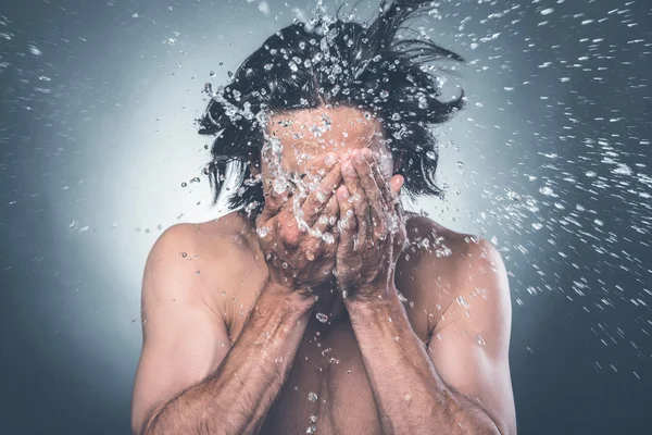 man washing face with water splashing
