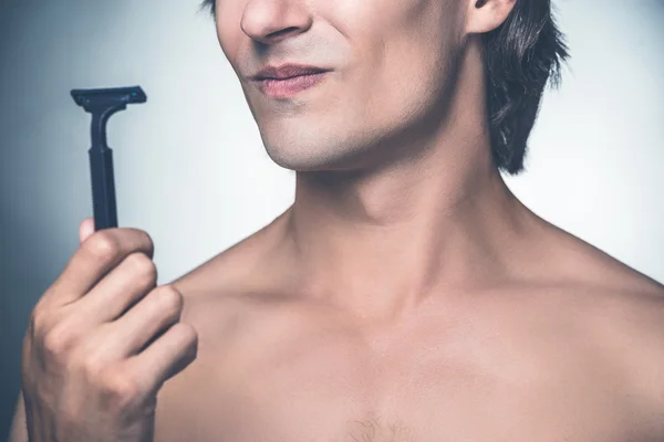 Young shirtless man holding razor