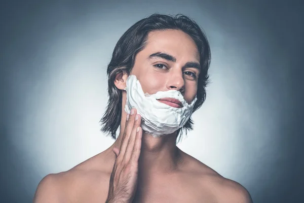 Man spreading shaving cream over face