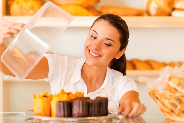 Woman in apron carrying plate with fresh cookies