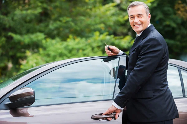 Mature man in formalwear standing near his new car