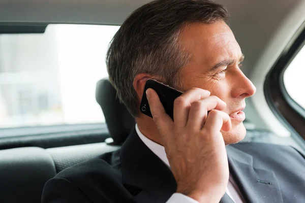 Businessman talking on mobile phone in car