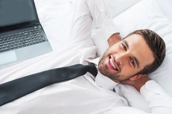 Man in shirt and tie lying in bed at hotel room