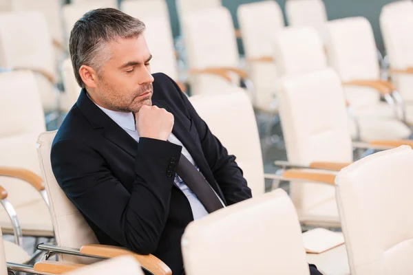 Bored mature man in formalwear in empty conference hall