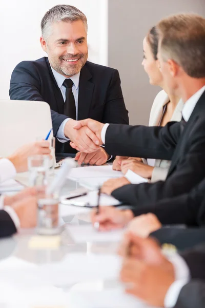 Man in formalwear shaking hand of his colleagues