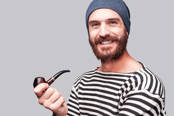 Bearded man in striped clothing holding a pipe