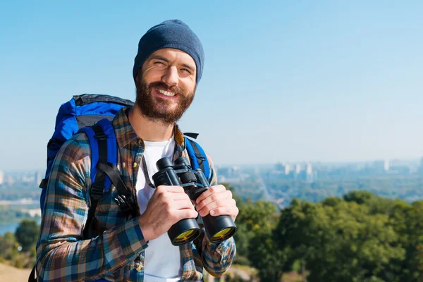 Man carrying backpack and holding binoculars