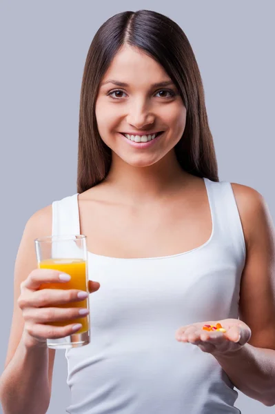 Woman holding glass with juice and pills