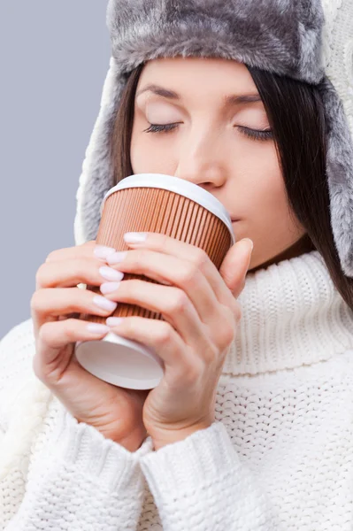 Woman in winter clothing and drinking coffee