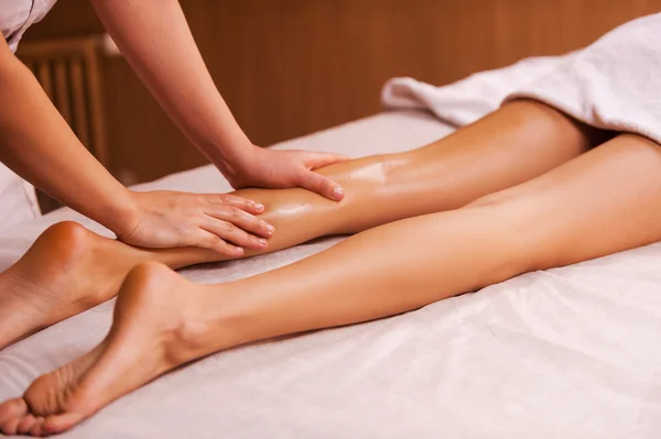 Massage therapist massaging female leg