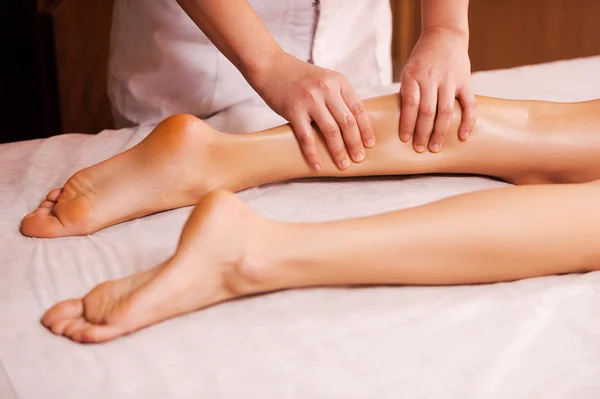 Massage therapist massaging female leg