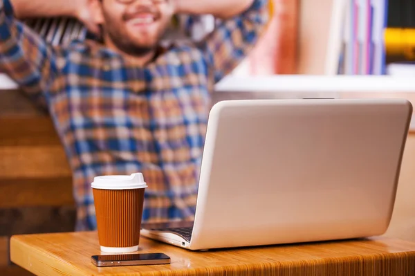 Man holding hand behind head and sitting at the desk