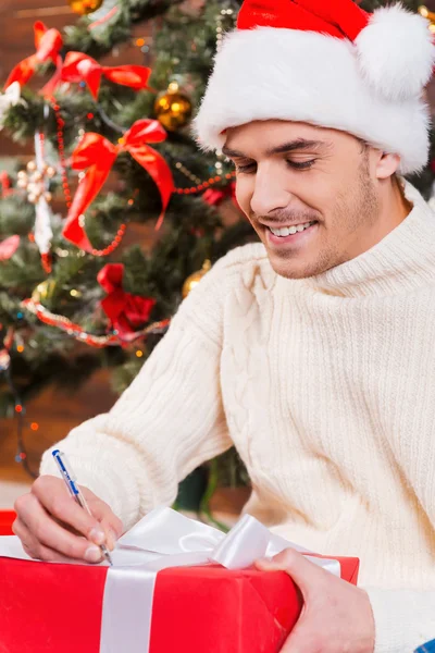 Man in Santa hat writing Christmas letter