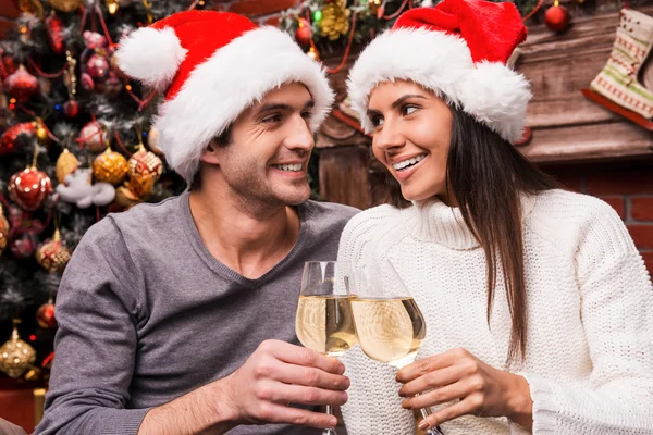 Loving couple in Santa hats cheering with wine