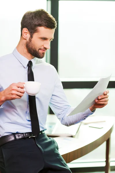 Man  holding coffee cup and examining document