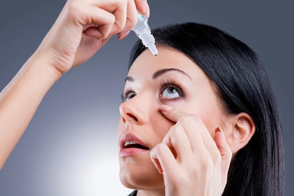 Young woman applying eye drops