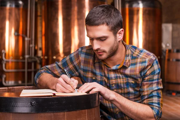 Young man in casual shirt writing in his note pad