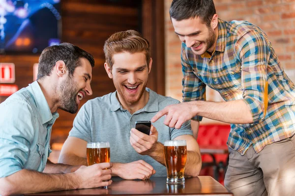 Men drinking beer in pub with smart phone