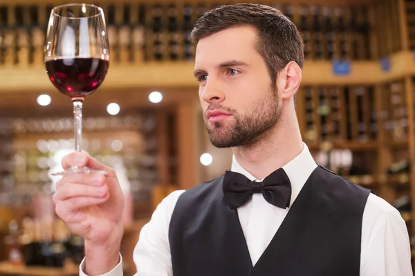 Confident man examining red wine