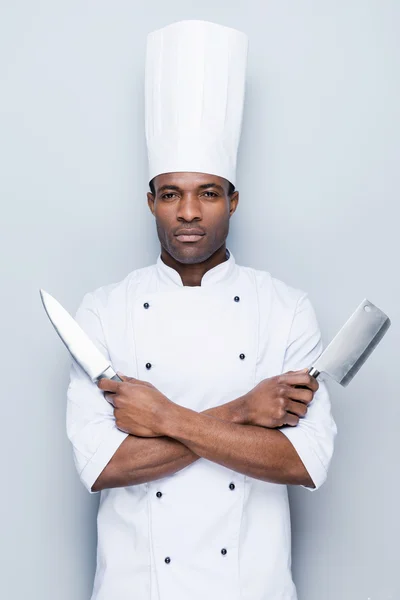 African chef in uniform holding knifes