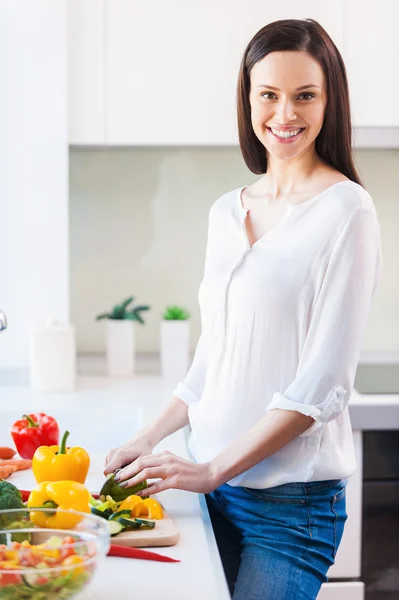 Young woman cutting vegetables and smiling