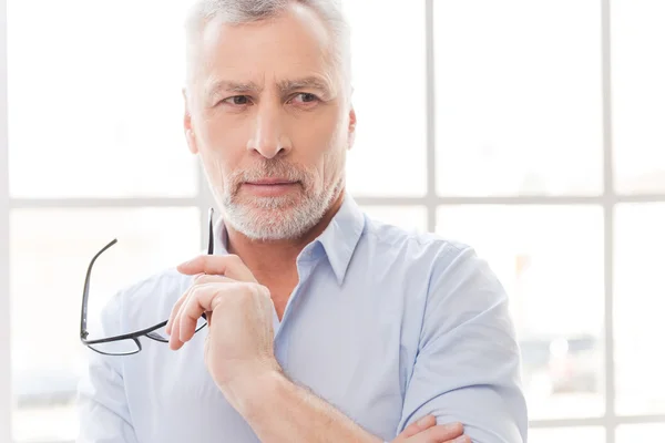 Senior man in shirt holding his eyeglasses