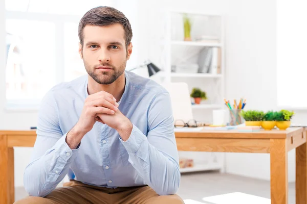 Man in shirt sitting in front of working place
