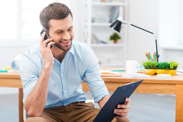 Man talking on telephone and looking at clipboard