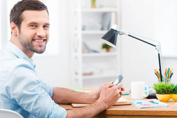 Man holding mobile phone sitting at working place