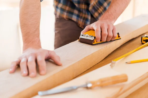 Carpenter sanding wood in workshop