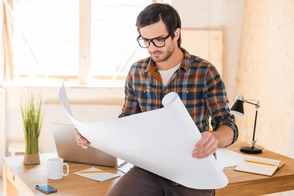 Man looking through blueprint at working place