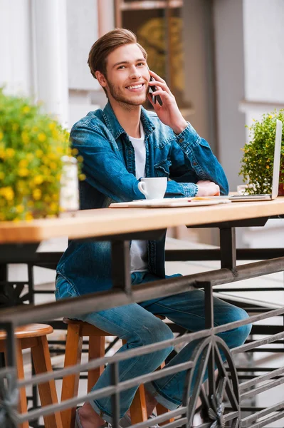 Man talking on mobile phone at sidewalk cafe