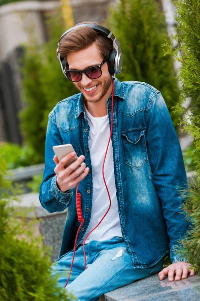 Man in headphones holding mobile phone