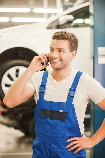Man talking on phone in workshop with car