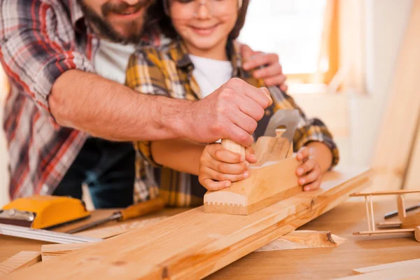 Carpenter teaching son to work with wood
