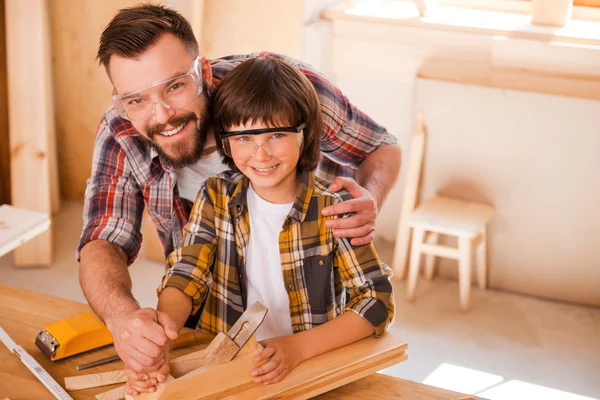 Carpenter teaching son to work with wood