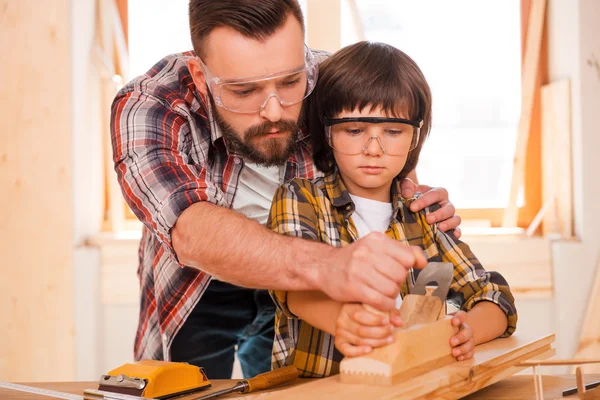 Carpenter teaching his son to work with wood