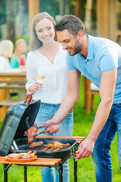 Couple barbecuing meat on the grill