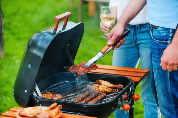 People barbecuing meat on the grill