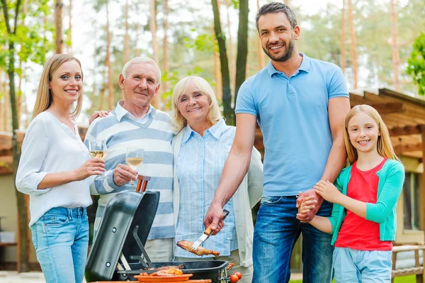 Family barbecuing meat on grill