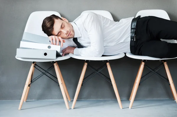Man keeping eyes closed while laying on chairs
