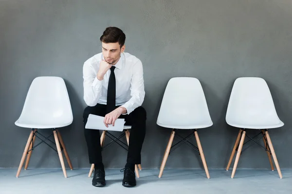 Pensive young businessman sitting on chair